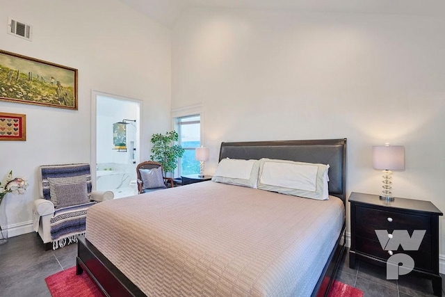 bedroom featuring ensuite bath and a high ceiling