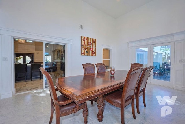 dining space featuring a towering ceiling, visible vents, and french doors