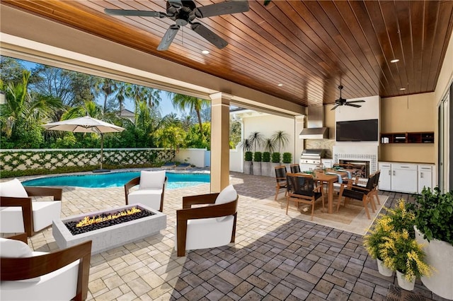 view of patio featuring a fenced in pool, a fire pit, ceiling fan, grilling area, and exterior kitchen