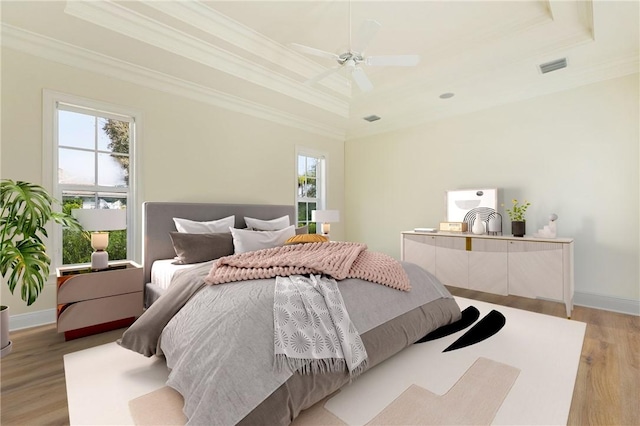 bedroom featuring ceiling fan, ornamental molding, a raised ceiling, and light hardwood / wood-style floors