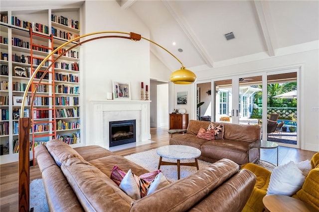 living room with beam ceiling, hardwood / wood-style flooring, high vaulted ceiling, and a premium fireplace