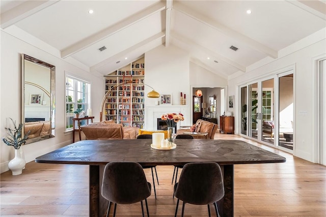 dining room featuring beamed ceiling, high vaulted ceiling, and light wood-type flooring