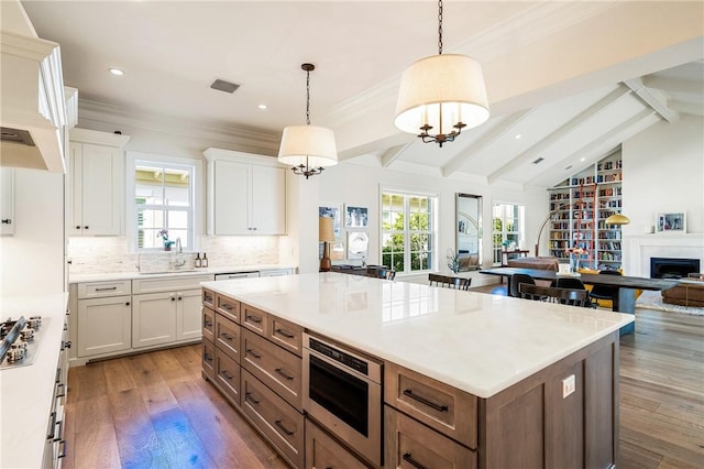 kitchen with sink, white cabinetry, decorative light fixtures, a center island, and dark hardwood / wood-style flooring