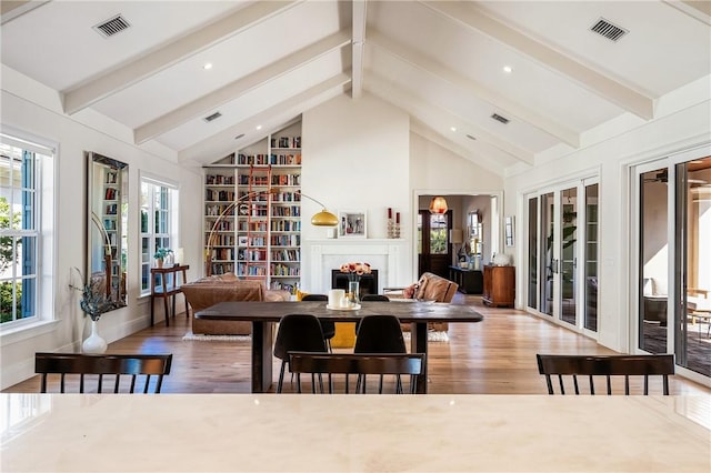 interior space featuring beamed ceiling, a wealth of natural light, hardwood / wood-style floors, and high vaulted ceiling