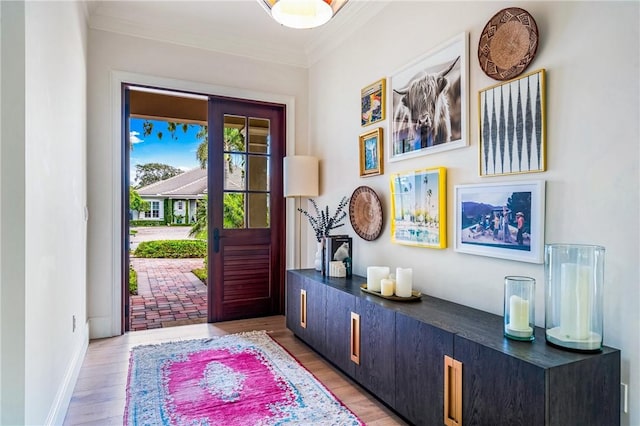 entryway with ornamental molding and light wood-type flooring