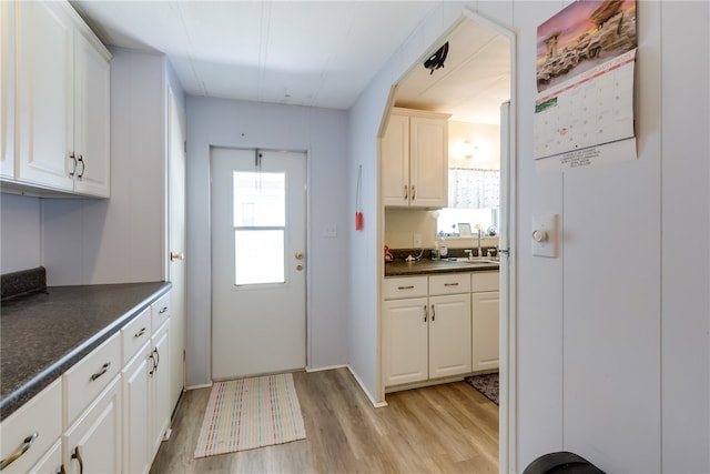 kitchen with white cabinetry, sink, and light hardwood / wood-style flooring