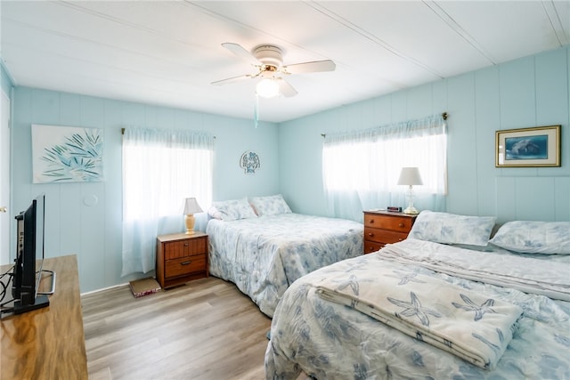 bedroom featuring ceiling fan, light hardwood / wood-style floors, and multiple windows