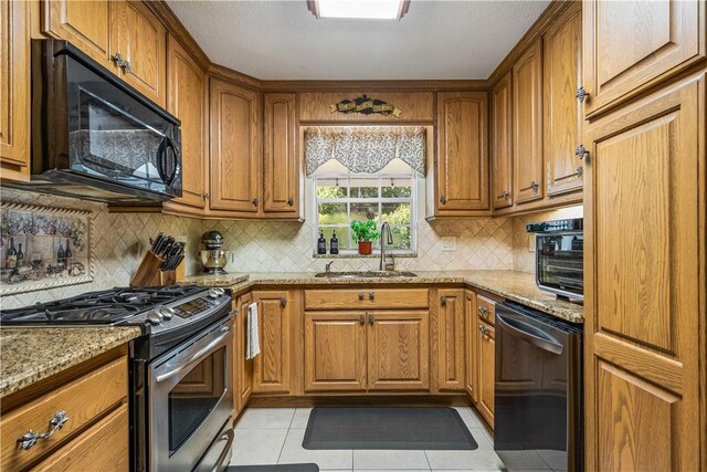 5845 23rd St, Vero Beach, FL 32966 - kitchen featuring stainless steel gas range, black microwave, dishwasher, a sink, and brown cabinets