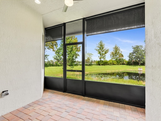 unfurnished sunroom with ceiling fan and a water view