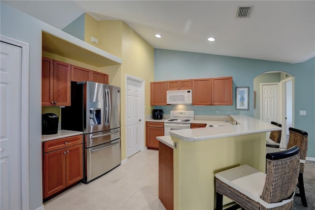 kitchen featuring high vaulted ceiling, light tile patterned floors, a kitchen breakfast bar, kitchen peninsula, and white appliances