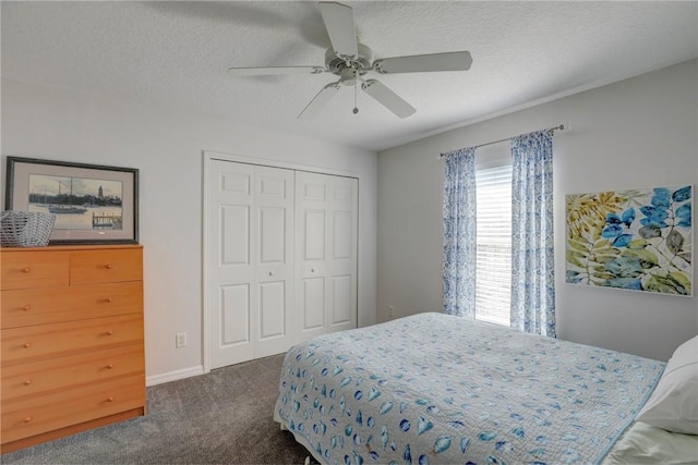 bedroom with ceiling fan, a textured ceiling, dark carpet, and a closet