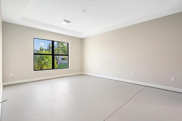 unfurnished room featuring a raised ceiling and concrete flooring