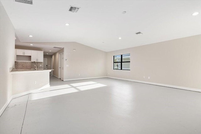 unfurnished living room with sink and lofted ceiling