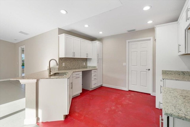 kitchen with white cabinetry, sink, kitchen peninsula, carpet floors, and decorative backsplash