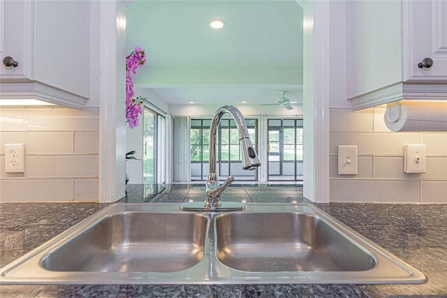 kitchen with tasteful backsplash, white cabinetry, sink, and ceiling fan