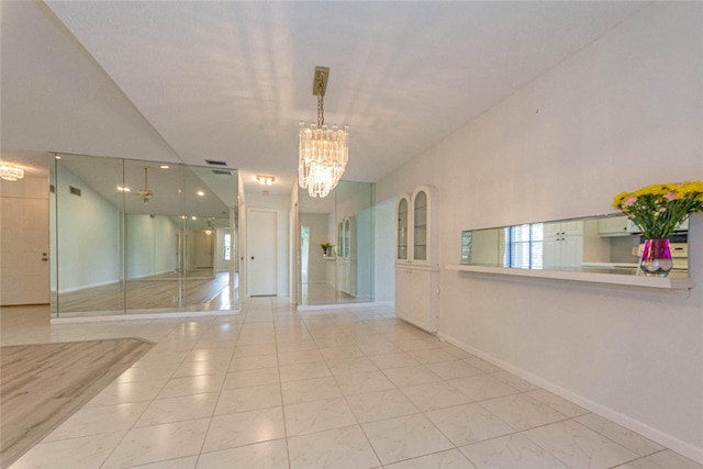 tiled spare room featuring a chandelier