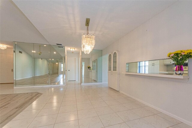 tiled spare room featuring a chandelier