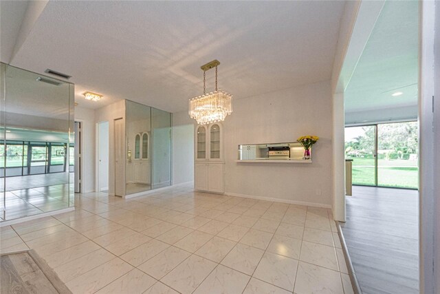 spare room featuring a textured ceiling and an inviting chandelier