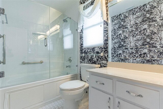 full bathroom featuring toilet, combined bath / shower with glass door, and vanity