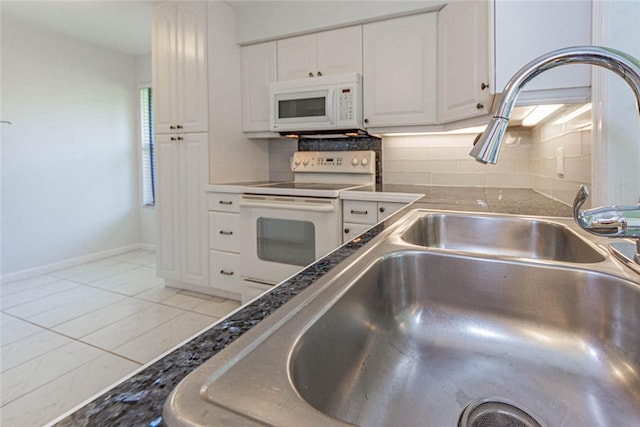 kitchen featuring white appliances, white cabinetry, light tile patterned floors, and backsplash