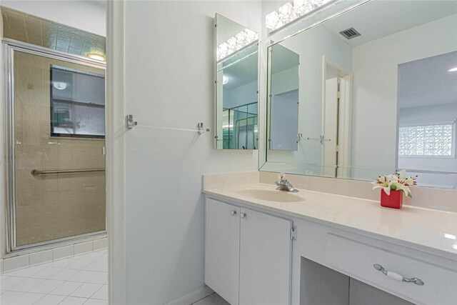 bathroom featuring walk in shower, vanity, and tile patterned floors