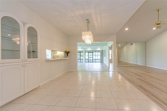 unfurnished room featuring light wood-type flooring and ceiling fan with notable chandelier