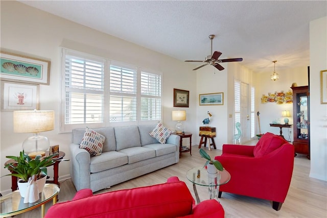 living area with light wood-style flooring, a ceiling fan, and a textured ceiling