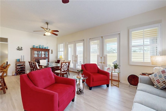 living room featuring ceiling fan, light hardwood / wood-style floors, and a textured ceiling