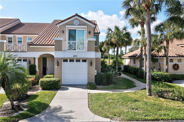 view of front of house featuring a tiled roof, concrete driveway, a front yard, stucco siding, and an attached garage