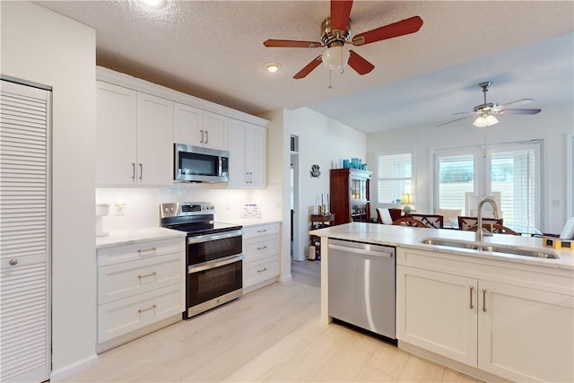 4853 N Newport Island Dr Unit 12B, Vero Beach, FL 32967 - kitchen with appliances with stainless steel finishes, ceiling fan, light countertops, light wood-style flooring, and white cabinets