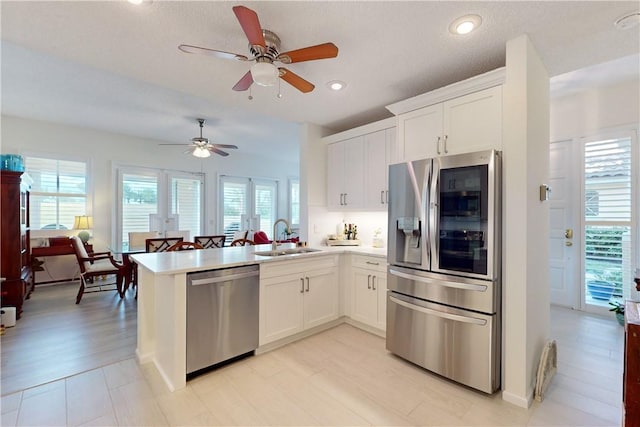 kitchen with sink, stainless steel appliances, kitchen peninsula, and white cabinets