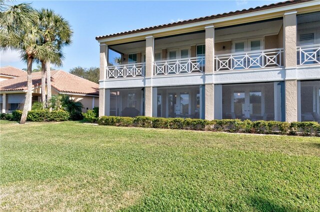 4853 N Newport Island Dr Unit 12B, Vero Beach, FL 32967 - rear view of house featuring french doors, a lawn, a balcony, and stucco siding
