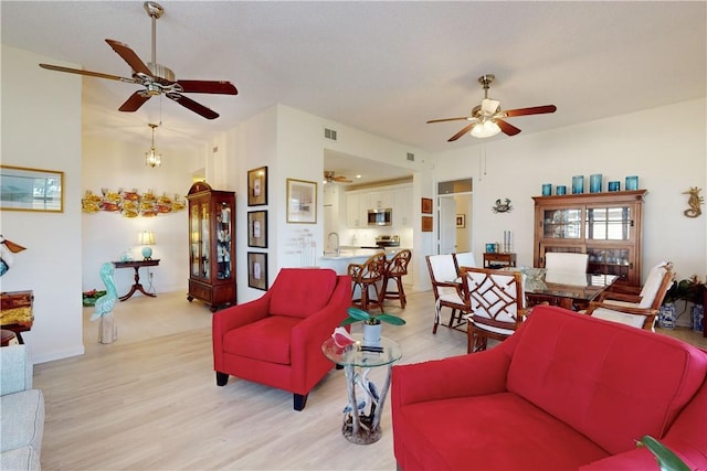 living room featuring baseboards, visible vents, ceiling fan, and light wood-style flooring