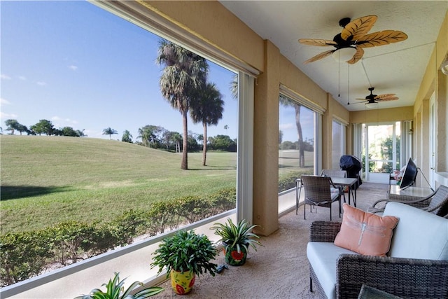 sunroom / solarium featuring a ceiling fan and a rural view