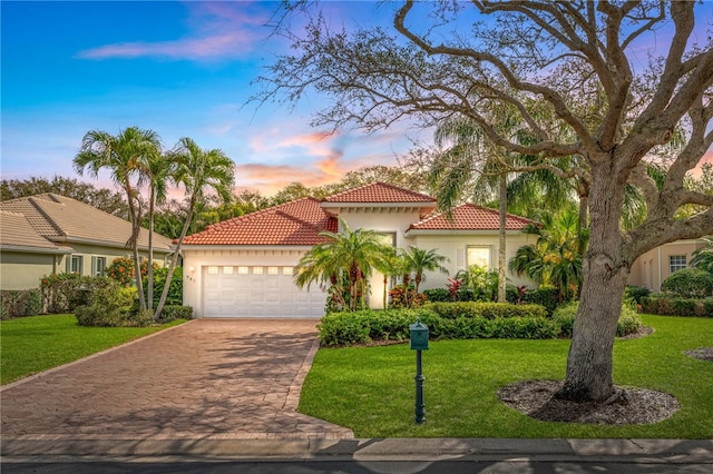 mediterranean / spanish-style home with a garage and a lawn