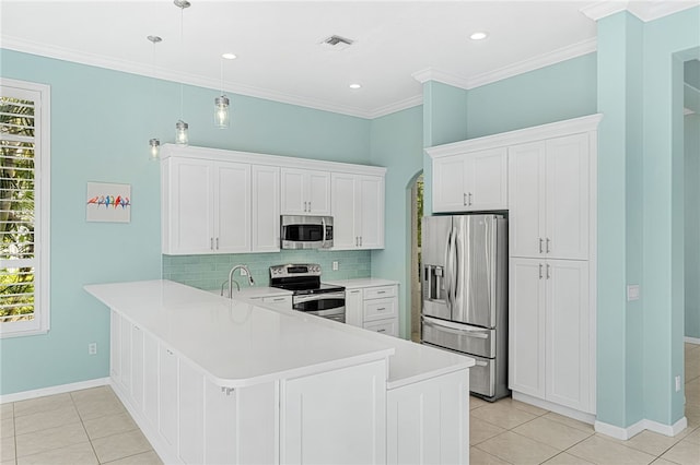 kitchen with appliances with stainless steel finishes, white cabinetry, kitchen peninsula, hanging light fixtures, and decorative backsplash