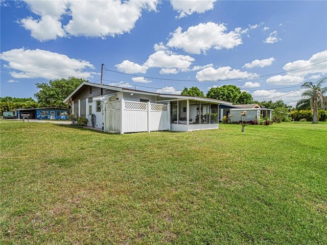 back of house featuring a sunroom and a yard