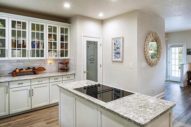 kitchen featuring white cabinets, light stone countertops, tasteful backsplash, and black electric cooktop