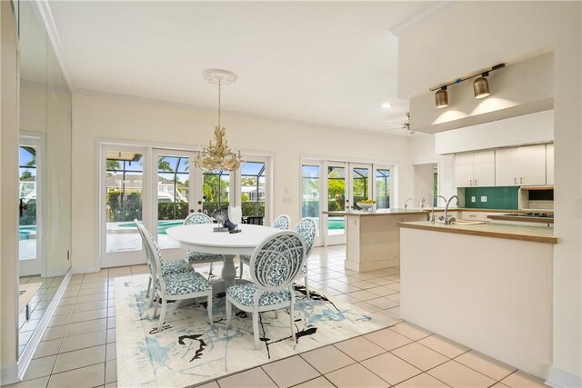 living room featuring light tile patterned flooring, crown molding, a raised ceiling, and a notable chandelier