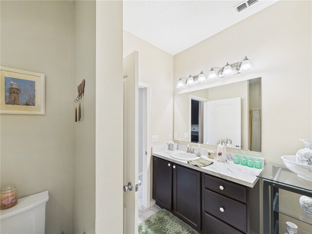 bathroom featuring visible vents, toilet, and vanity