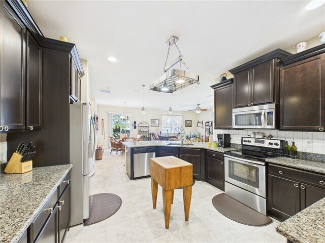 kitchen featuring pendant lighting, backsplash, light stone countertops, and appliances with stainless steel finishes