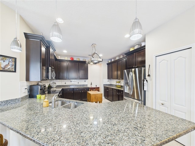 kitchen with a peninsula, a sink, decorative backsplash, dark brown cabinets, and appliances with stainless steel finishes