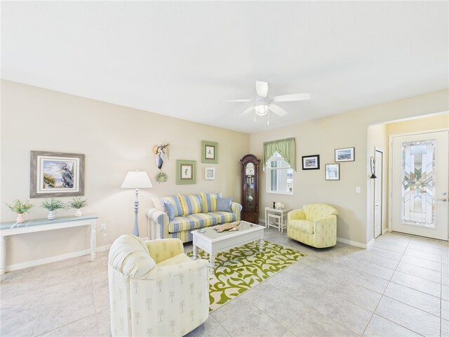 living room with light tile patterned floors, ceiling fan, and baseboards