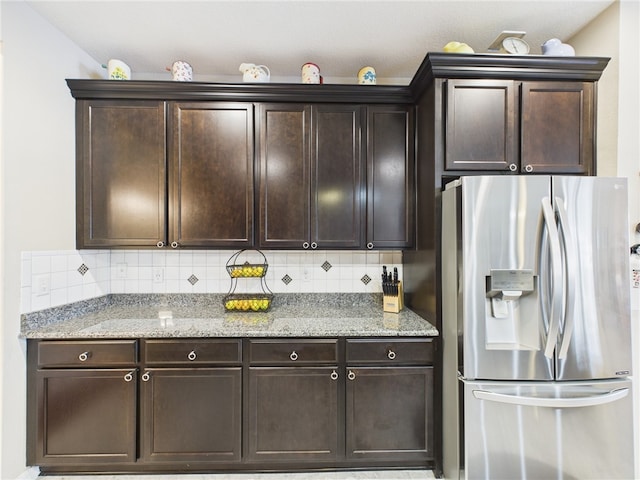 kitchen with decorative backsplash, dark brown cabinets, and stainless steel refrigerator with ice dispenser