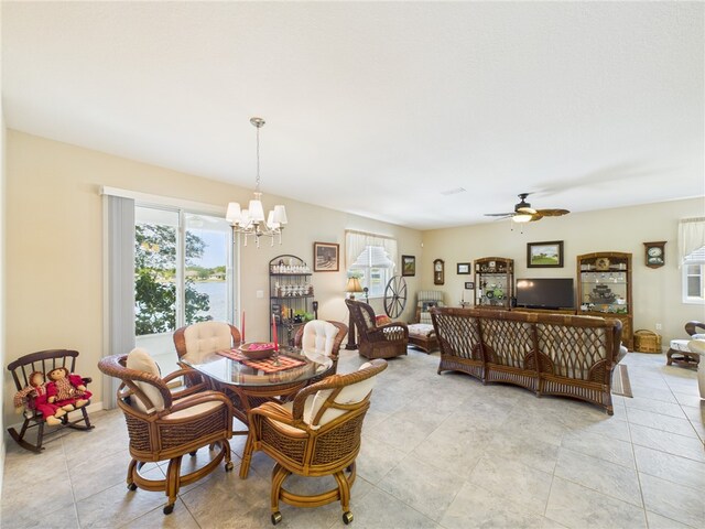 dining space with light tile patterned floors, ceiling fan with notable chandelier, and a healthy amount of sunlight
