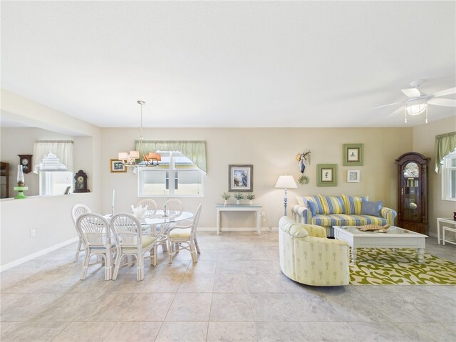 living room with light tile patterned floors, baseboards, and ceiling fan with notable chandelier