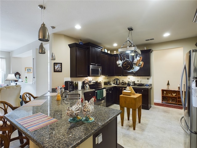 kitchen with pendant lighting, decorative backsplash, stainless steel appliances, and dark stone counters