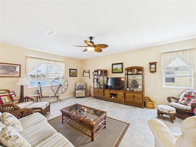 tiled living room featuring a ceiling fan, visible vents, and baseboards