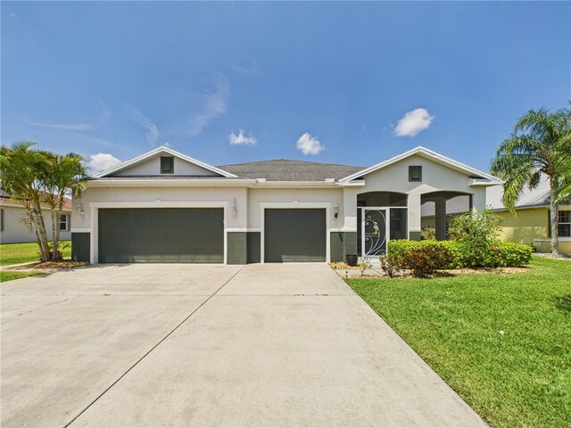 ranch-style house featuring a garage, a front lawn, stucco siding, and driveway