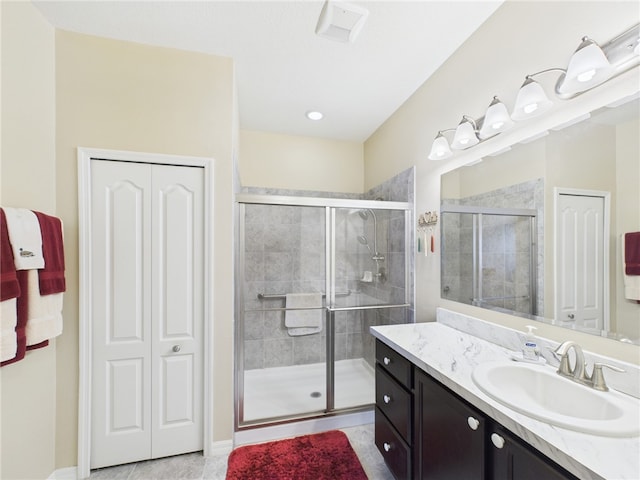 bathroom featuring a shower stall, vanity, visible vents, baseboards, and tile patterned flooring